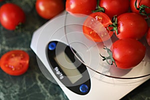 Fresh tomatoes on kitchen scales weighing