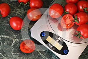 Fresh tomatoes on kitchen scales weighing