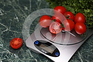 Fresh tomatoes on kitchen scales weighing