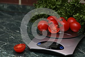 Fresh tomatoes on kitchen scales weighing