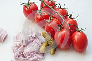 Fresh tomatoes, onions and pickles on plastic cutting board