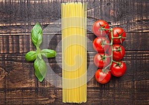 Fresh tomatoes with raw spagetti and basil on gunge background