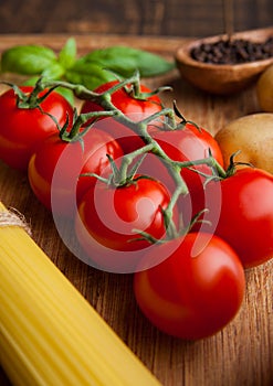 Fresh tomatoes with raw spagetti and pepper on kitchen board