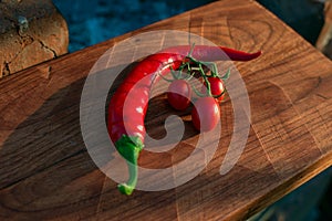 Fresh tomatoes and red pepper on wooden board, selective focus