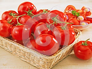 Fresh tomatoes in a wicker basket on table