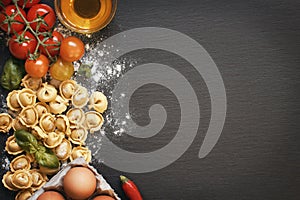 Fresh tortellini pasta and ingredients on a dark board