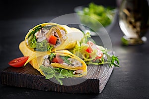 Fresh tortilla wraps with chicken and fresh vegetables on wooden board.