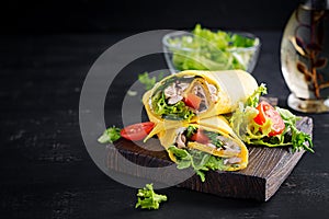 Fresh tortilla wraps with chicken and fresh vegetables on wooden board.