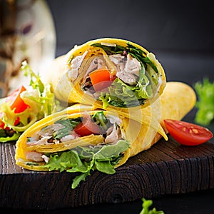 Fresh tortilla wraps with chicken and fresh vegetables on wooden board. Chicken burrito