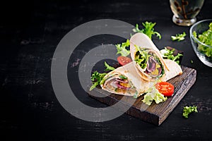 Fresh tortilla wraps with ham beef and fresh vegetables on wooden board.