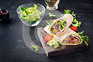 Fresh tortilla wraps with ham beef and fresh vegetables on wooden board. Beef burrito.