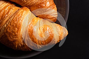 Fresh traditional croissants on a black background. Top view, Copy space