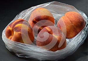 Fresh tree ripened peaches in plastic grocery store produce bag