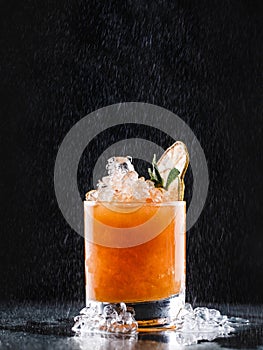 Fresh tropic cocktail with orange and berries in glass on black background. Summer drinks and alcoholic cocktails