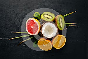 Fresh Tropical Fruits. Pineapple, coconut, kiwi, orange, pomegranate, grapefruit. On a wooden background. Top view.