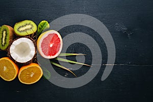 Fresh Tropical Fruits. Coconut, orange, kiwi and grapefruit. On a wooden background. Top view.