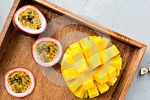 Fresh tropical fruits: mango and passion fruit on wooden background. Flatlay, top view, overhead. Healthy lifestyle and summer