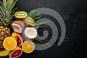 Fresh Tropical Fruits. Pineapple, coconut, kiwi, orange, pomegranate, grapefruit. On a wooden background. Top view.