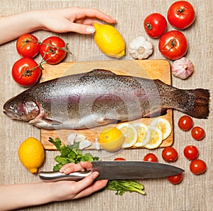 Fresh trout with vegetables on cutting board.