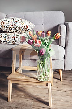 Fresh tulips bouquet in vase are in living room. Cozy home decor