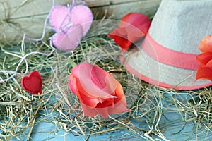 Fresh tulips, hearts decor, straw hat, hay on a wooden surface, top view