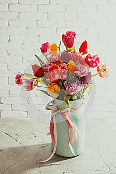 Fresh tulips in metal can on white table