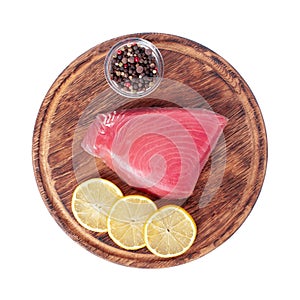 Fresh tuna fillet on wooden board. Fish steak on a cutting board with lemon slices and allspice. Red fish textured steak