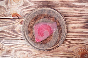 Fresh tuna fillet on wooden board. Fish steak on a cutting board. Red fish textured steak isolated
