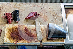 Fresh tuna fish cut in pieces ready for sale in a fish market with big knife and blood