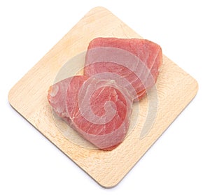 Fresh tuna Fish steak on a wooden cutting serving board isolated on a white background