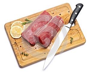 Fresh tuna Fish steak on a wooden cutting serving board isolated on a white background