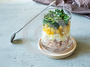 Fresh tuna salad with egg corn greens in a glass Cup on a concrete table. copy space