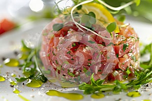 Fresh Tuna Tartare with Lemon, Herbs and Olive Oil Dressing on Elegant White Plate, Healthy Gourmet Appetizer