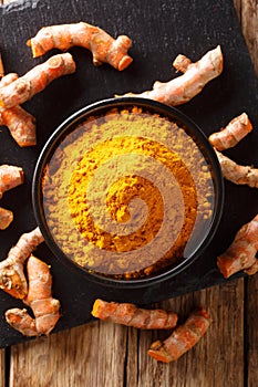 Fresh turmeric spice in a bowl and root close-up. Vertical top view