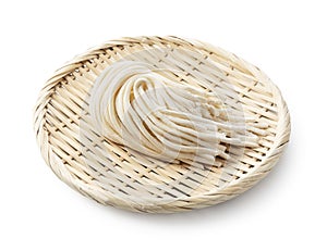 Fresh udon noodles in a bamboo colander placed on a white background