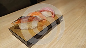 Fresh Unagi, salmon, and tuna nigiri sushi on a wooden platter