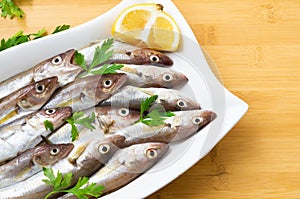 Fresh uncooked haddock fishes on in ceramic dish on table