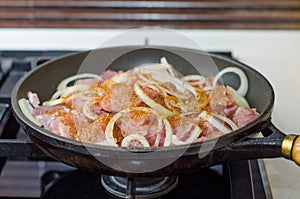 Fresh uncooked meat in frying pan on metal gas cooker