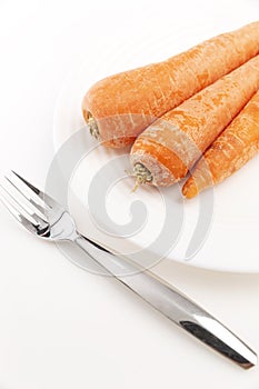 Fresh unpeeled carrots on a plate on a white background. Healthy and delicious vegetarian food.