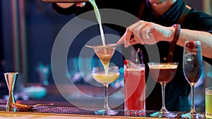 Fresh up your night. Close up of hands of male bartender pouring, mixing ingredients while making cocktails, alcoholic