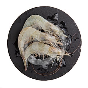 Fresh Vannamei shrimps, whiteleg shrimp, Pacific white shrimp or king prawn on black slate board isolated on white. Top view, photo