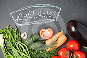 Fresh vegetable on graphite board with an inscription. Top view. onion, garlic , parsley , cucumber , eggplant , tomato and dill