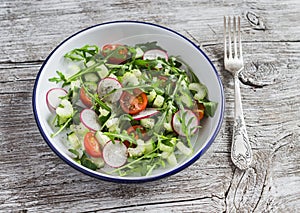 Fresh vegetable salad with cherry tomatoes, cucumbers, radishes and arugula. Healthy vegetarian food.