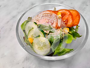 Fresh vegetable salad lettuce, corn, cucumber, tomato with roasted sesame Japanese dressing in glass bowl