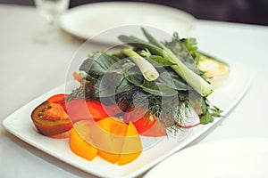 Fresh vegetable salad with radish, cucumber, bell pepper, tomatoes and herbs in a ceramic bowl restaurant dish. Selective focus