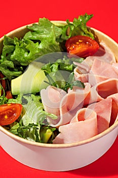 Fresh vegetable salad with slices of ham , cherry tomatoes, avocado, mix lettuce leaves. Ham salad. Take away food. Isolated