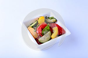 Fresh vegetable salad with tomato, cucumber, bell pepper and lettuce leaf in white bowl.