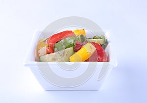 Fresh vegetable salad with tomato, cucumber, bell pepper and lettuce leaf in white bowl.