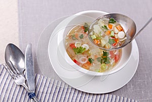 Fresh vegetable soup made of cabbage, carrot, potato, red bell pepper, tomato in bowl