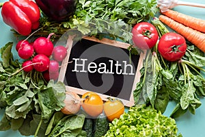 Fresh vegetables around black desk with text `Health`on blue background.